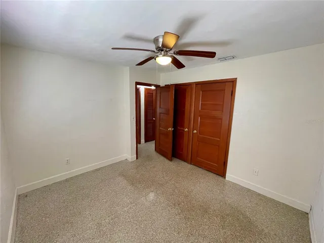 an empty room with closet and a ceiling fan