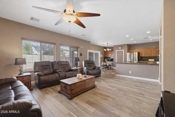a living room with furniture kitchen view and a wooden floor