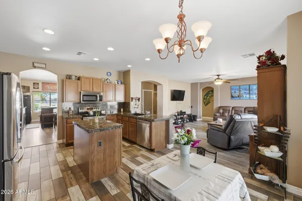 a living room with stainless steel appliances kitchen island granite countertop furniture a rug kitchen view and a chandelier