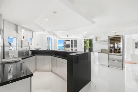 a kitchen with stainless steel appliances kitchen island granite countertop a refrigerator and a sink
