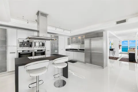 a kitchen with stainless steel appliances kitchen island granite countertop a sink refrigerator and cabinets
