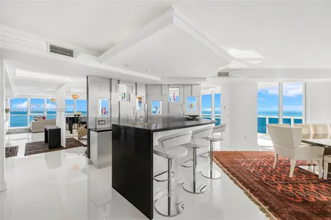 a kitchen with stainless steel appliances kitchen island granite countertop a table chairs and a refrigerator