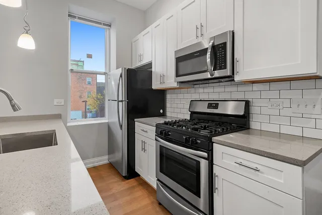 a kitchen with stainless steel appliances granite countertop a stove a sink and a refrigerator