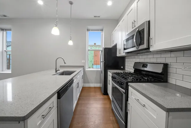 a view of kitchen with kitchen island stainless steel appliances sink refrigerator and microwave