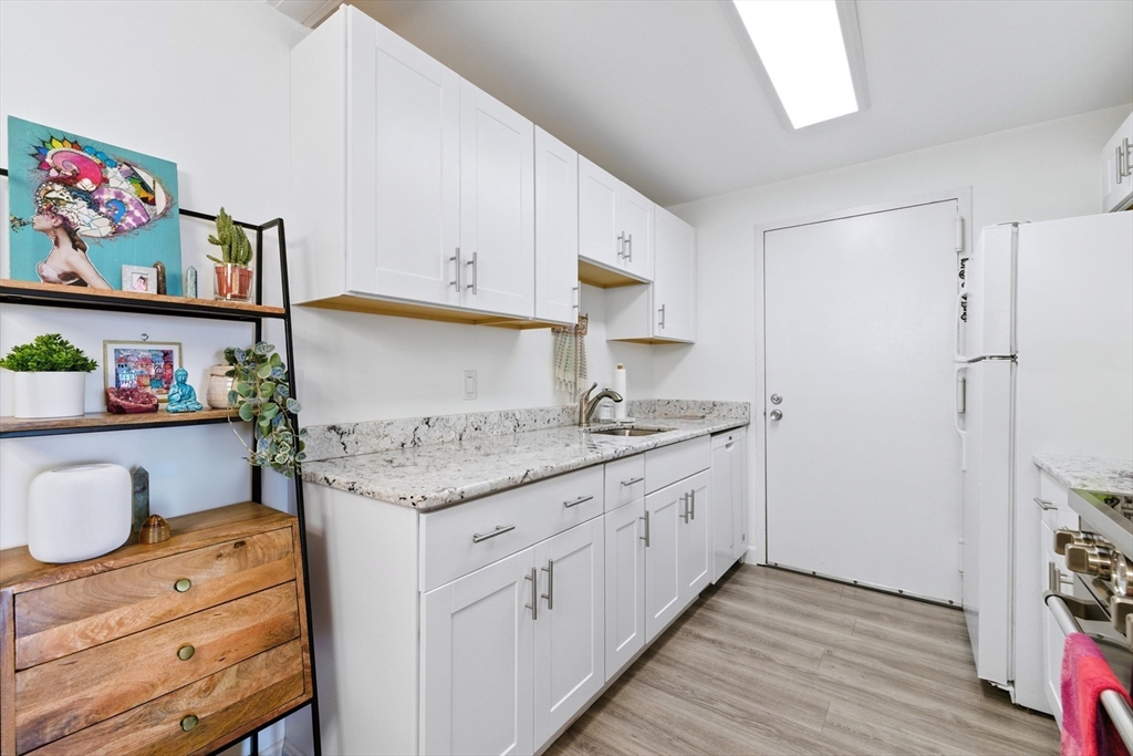 3 Post Oak Lane, Unit 1 Natick, MA 01760 - Photo 5 of 13 a kitchen with granite countertop a white stove top oven and cabinets