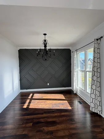 an empty room with wooden floor fireplace and windows