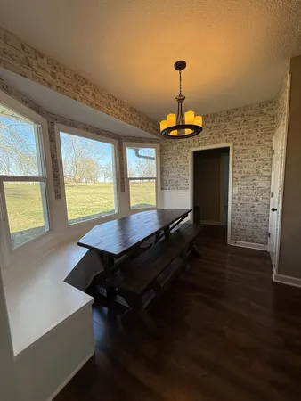 a dining room with wooden floor a chandelier a wooden table and chairs