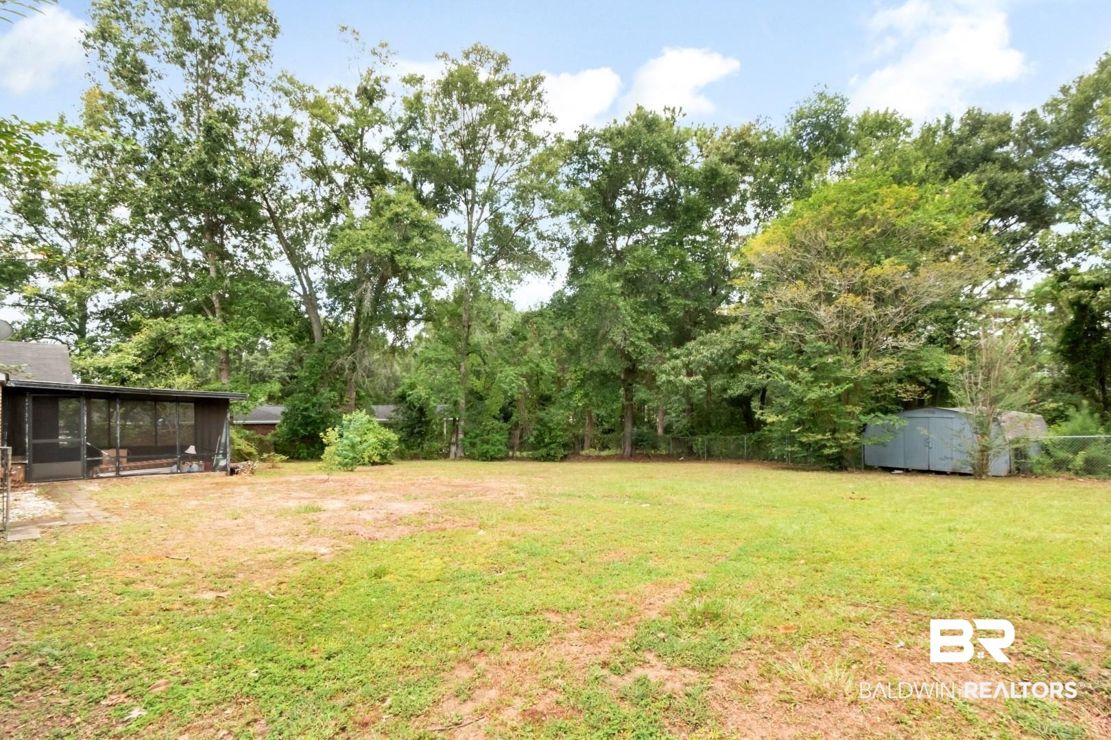 5812 Fern Valley Road Mobile, AL 36609 - Photo 31 of 32 Expansive backyard featuring a large lawn area, mature trees bordering the property, a screened porch, and a storage shed
