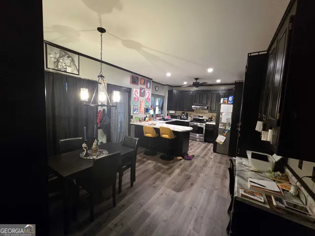 a kitchen with stainless steel appliances kitchen island granite countertop a refrigerator a stove and a sink with wooden floor