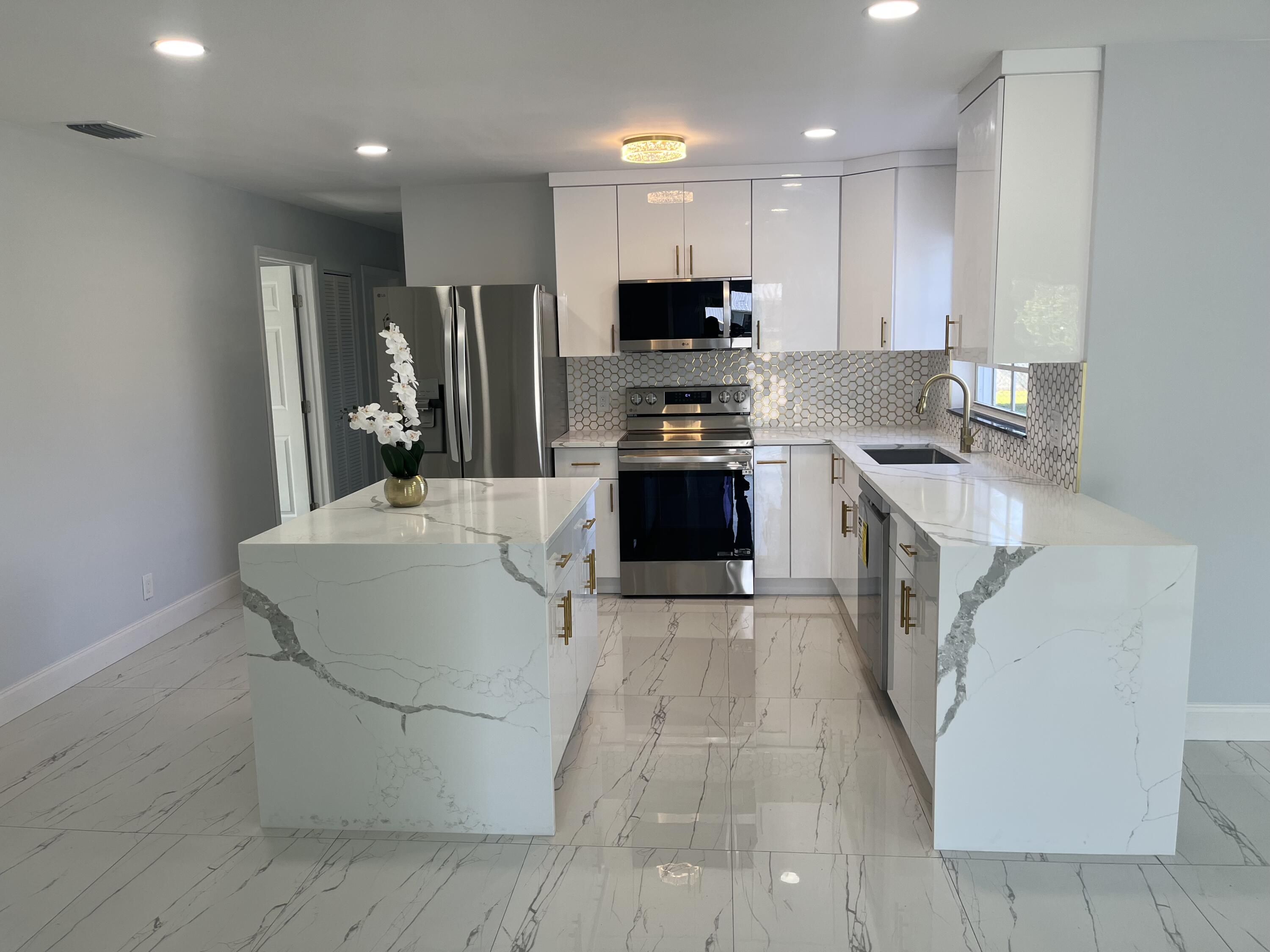 a large white kitchen with wooden floor and stainless steel appliances