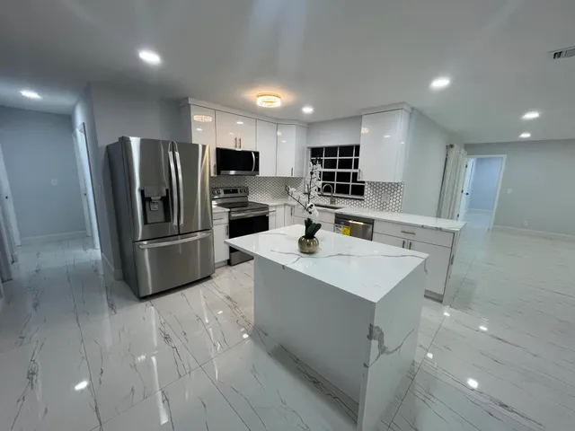 a kitchen with kitchen island a sink stainless steel appliances and cabinets