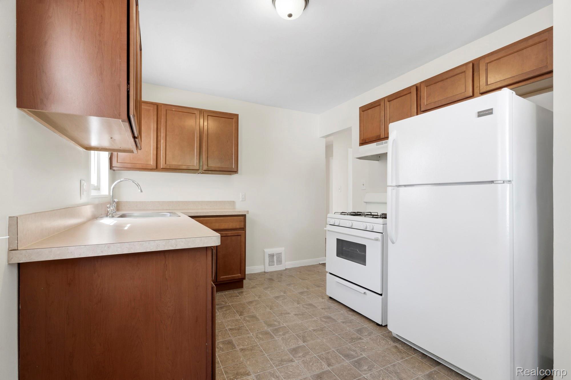 970 Champaign Road Lincoln Park, MI 48146 - Photo 17 of 28 Kitchen featuring white appliances, wood finish cabinetry, and light countertops