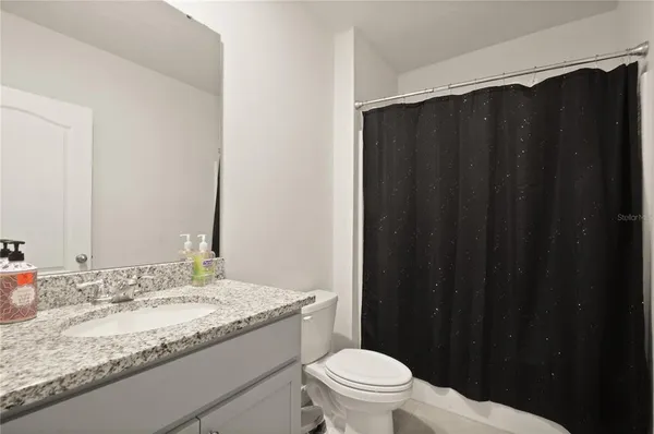 a bathroom with a granite countertop sink and a toilet