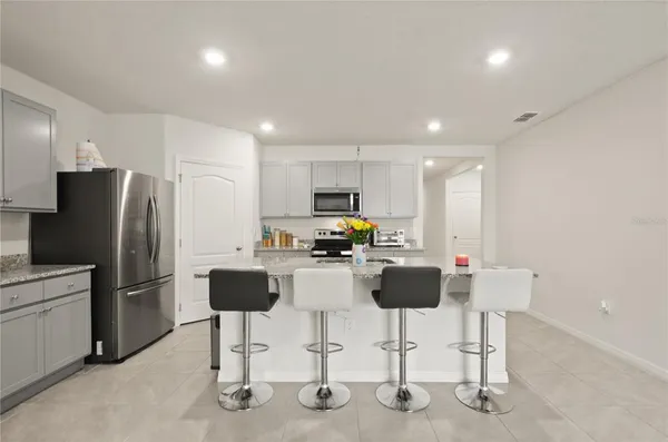 a kitchen with stainless steel appliances kitchen island granite countertop a refrigerator and a stove top oven with white cabinets