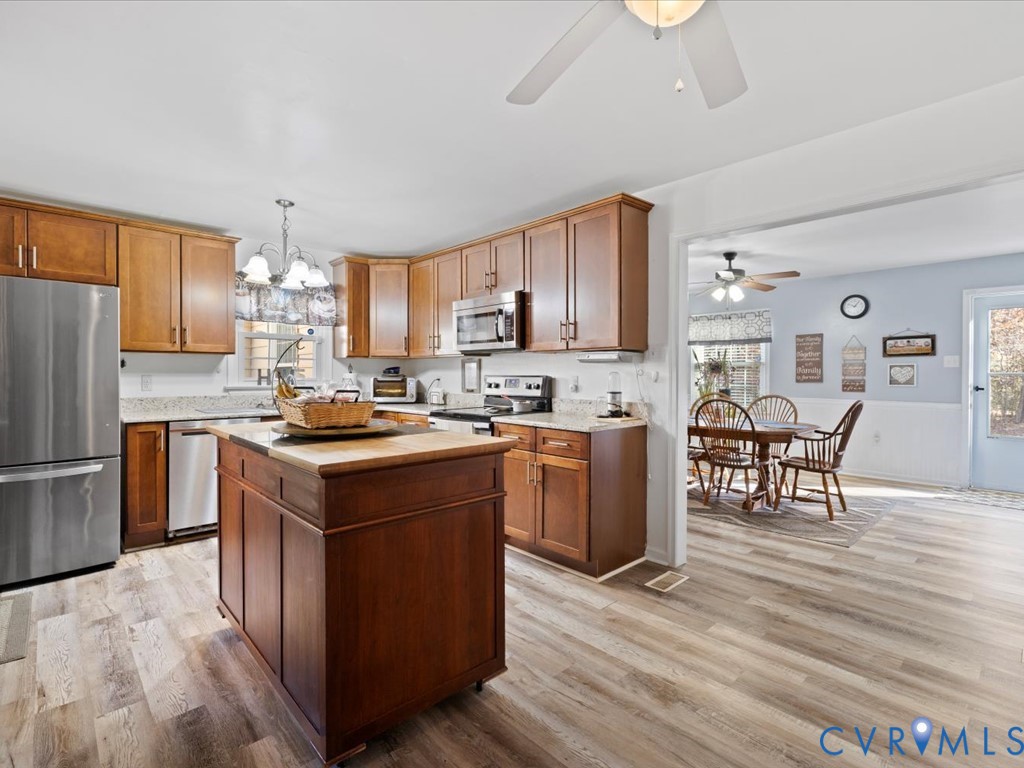 15415 Hopeful Church Road Bumpass, VA 23024 - Photo 6 of 27 a kitchen with stainless steel appliances granite countertop a stove top oven a sink dishwasher a refrigerator and a dining table with wooden floor