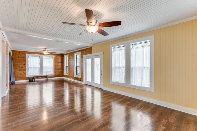 a view of an empty room with wooden floor and a window