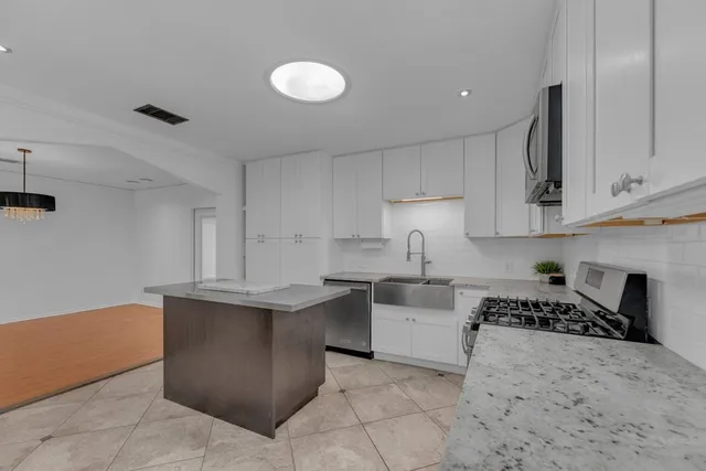 a kitchen with granite countertop white cabinets and stainless steel appliances