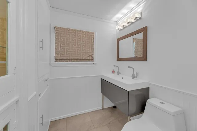 a bathroom with a toilet sink vanity and mirror