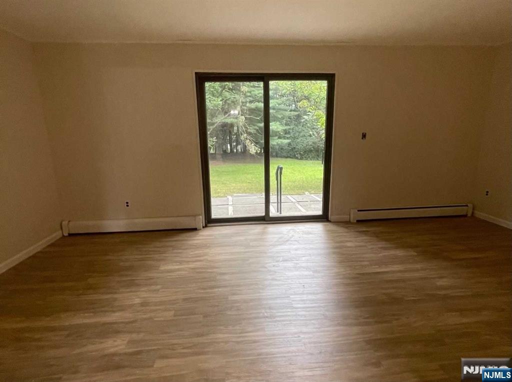 338 Queens Court Ridgewood, NJ 07450 - Photo 7 of 25 a view of an empty room with wooden floor and a window