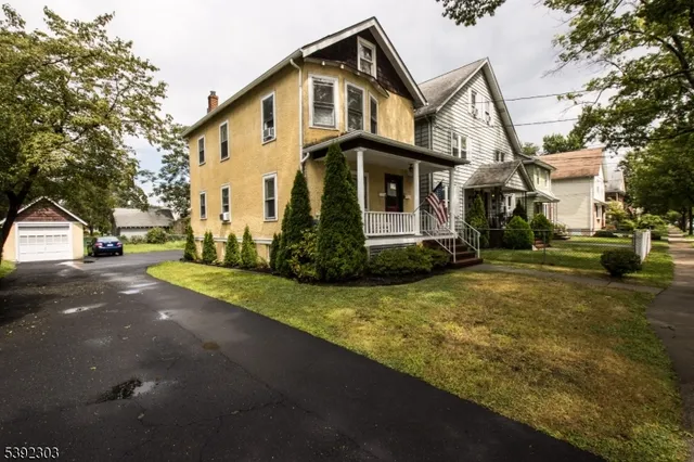 a view of a white house next to a road and yard