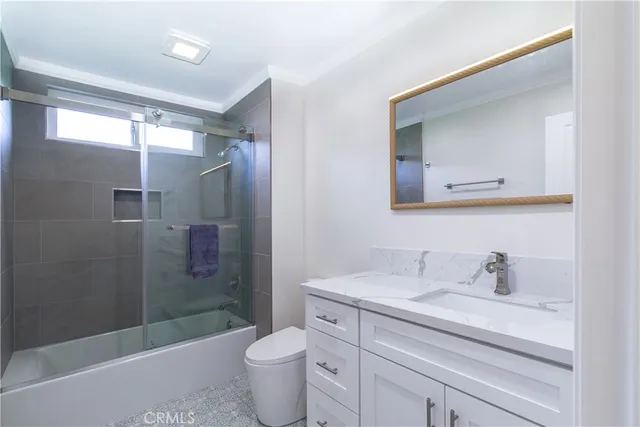 a bathroom with a granite countertop sink a toilet and shower