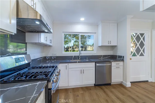 a kitchen with stainless steel appliances granite countertop a stove a sink and a microwave
