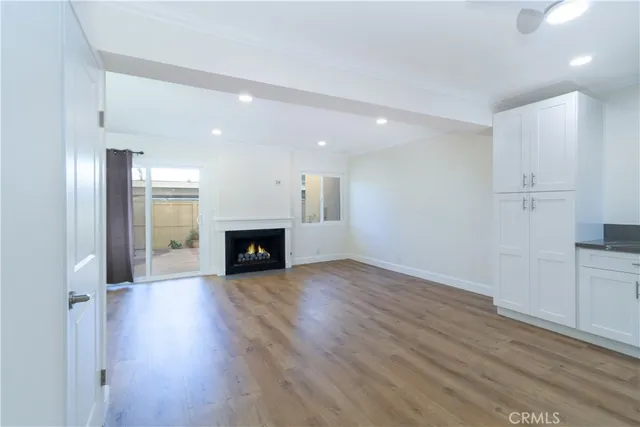 an empty room with wooden floor fireplace and windows