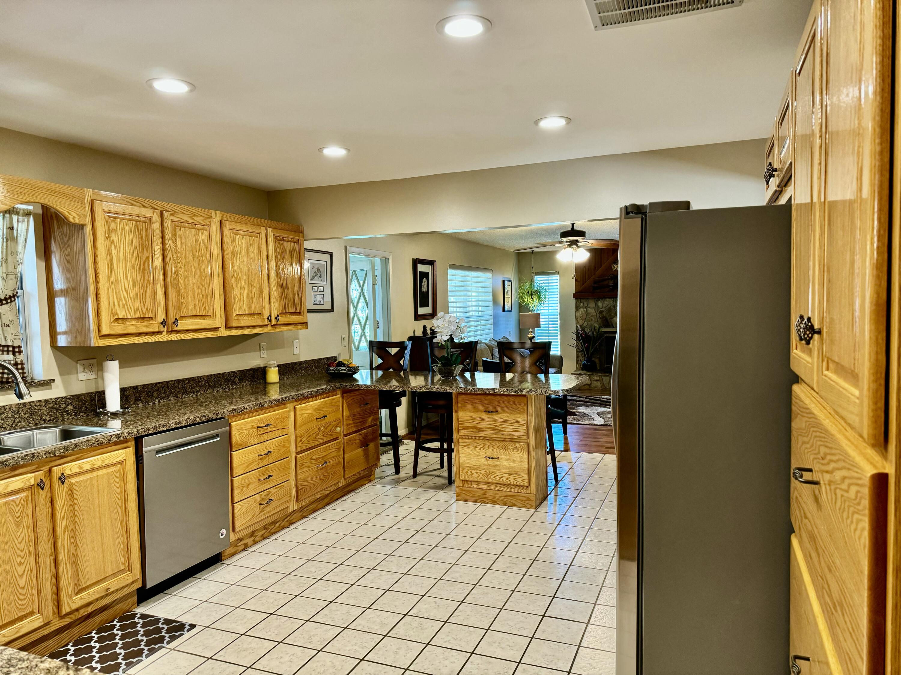 1515 Southwest 19th Terrace Okeechobee, FL 34974 - Photo 13 of 39 a kitchen with stainless steel appliances granite countertop a refrigerator a sink dishwasher a dining table and chairs with wooden floor
