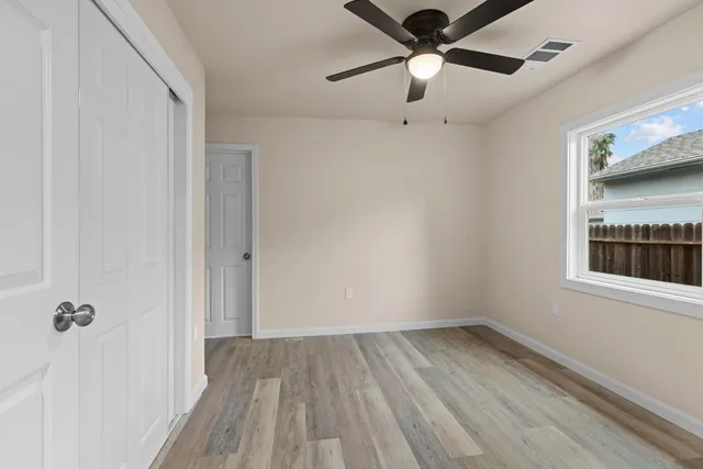 a view of a hallway with a ceiling fan and wooden floor