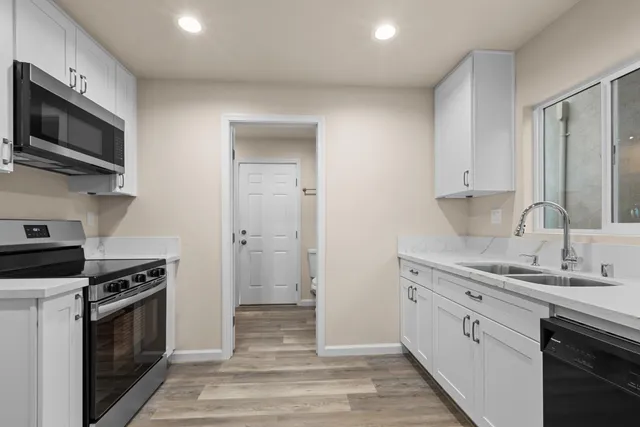 a kitchen with stainless steel appliances a stove microwave and sink