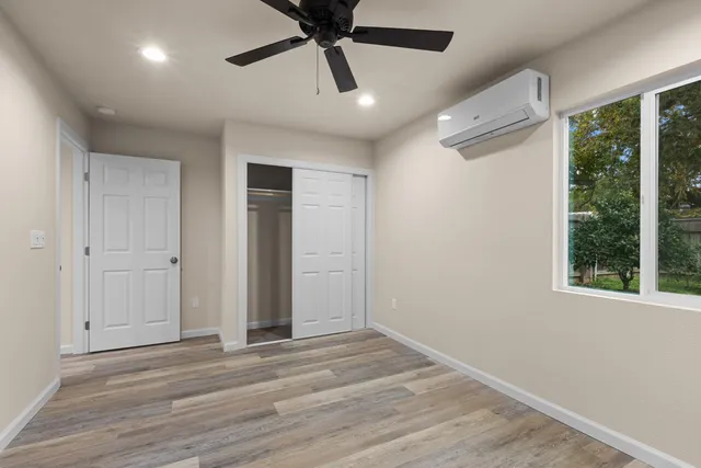 a view of an empty room with wooden floor and window