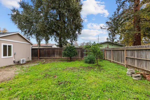 a view of a backyard with wooden fence and a large tree