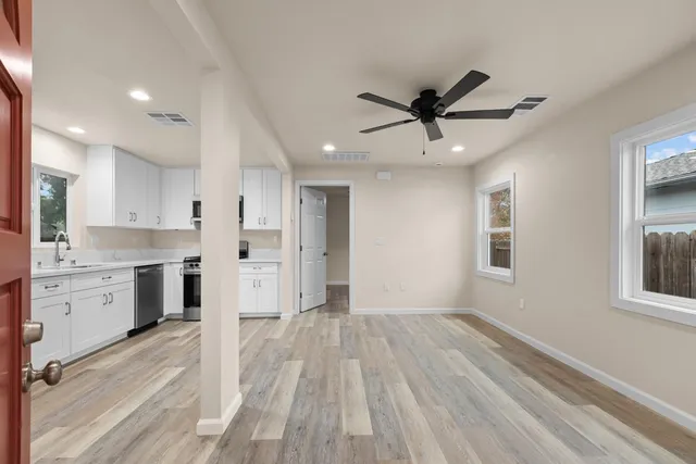 a open kitchen with white cabinets and wooden floor