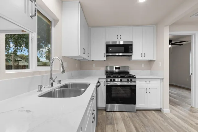 a kitchen with stainless steel appliances granite countertop a stove a sink and a microwave