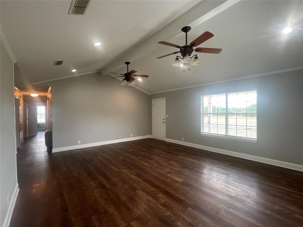 180 Cr 3320 Road Avery, TX 75554 - Photo 5 of 18 an empty room with wooden floor a ceiling fan and windows