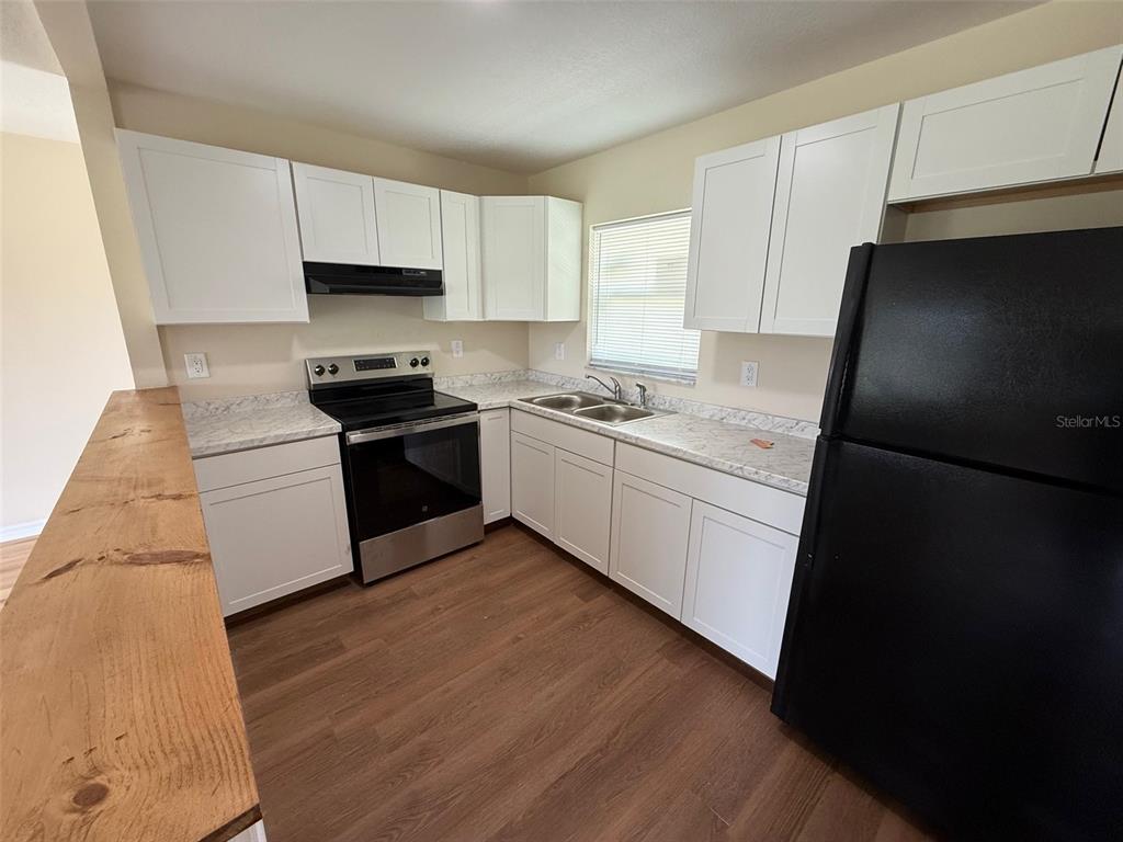 7319 Holiday Drive Spring Hill, FL 34606 - Photo 5 of 20 a kitchen with stainless steel appliances a sink dishwasher a refrigerator a stove top oven a sink and dishwasher with wooden floor