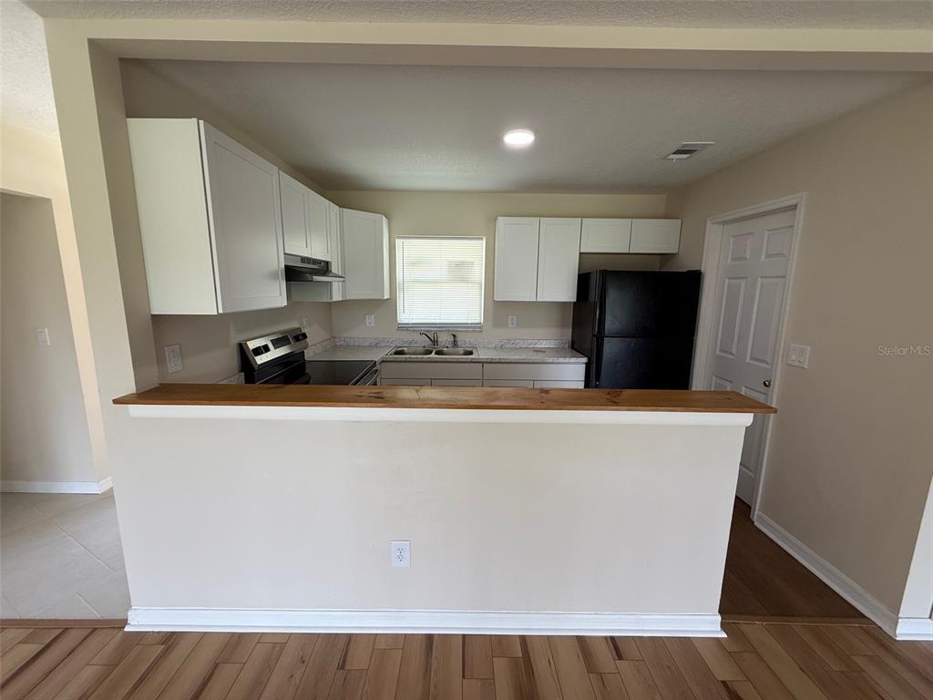 7319 Holiday Drive Spring Hill, FL 34606 - Photo 7 of 20 a living room with stainless steel appliances a refrigerator a stove a microwave and cabinets
