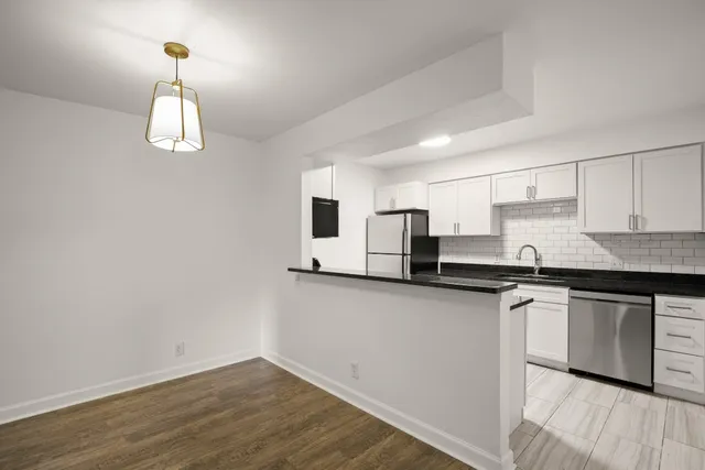 a kitchen with stainless steel appliances granite countertop a sink dishwasher a stove and white countertops with wooden floor