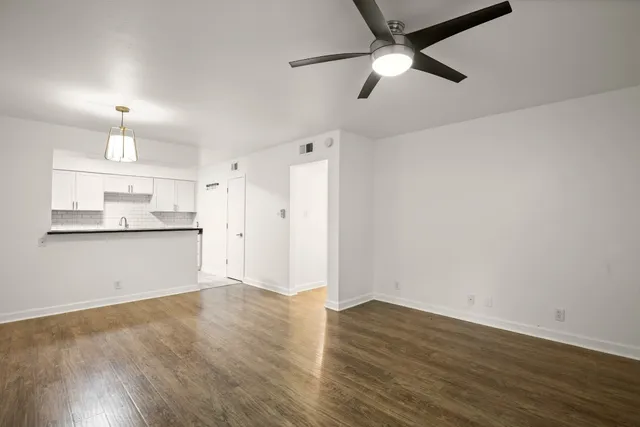 a view of a kitchen with wooden floor a sink a refrigerator and window