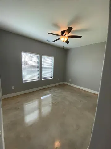 an empty room with windows and fan
