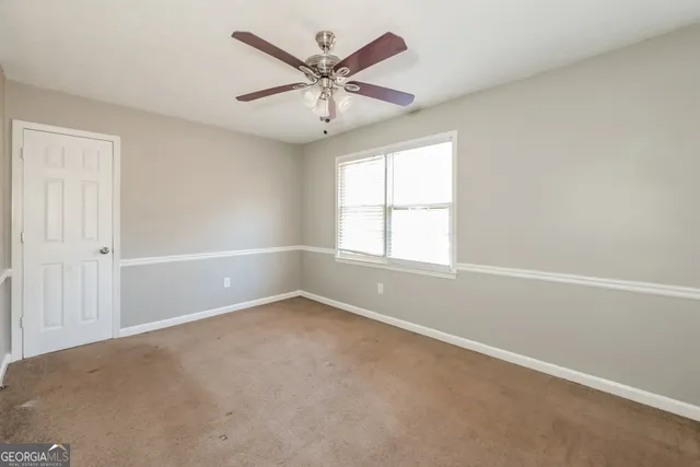 an empty room with a window and a fan