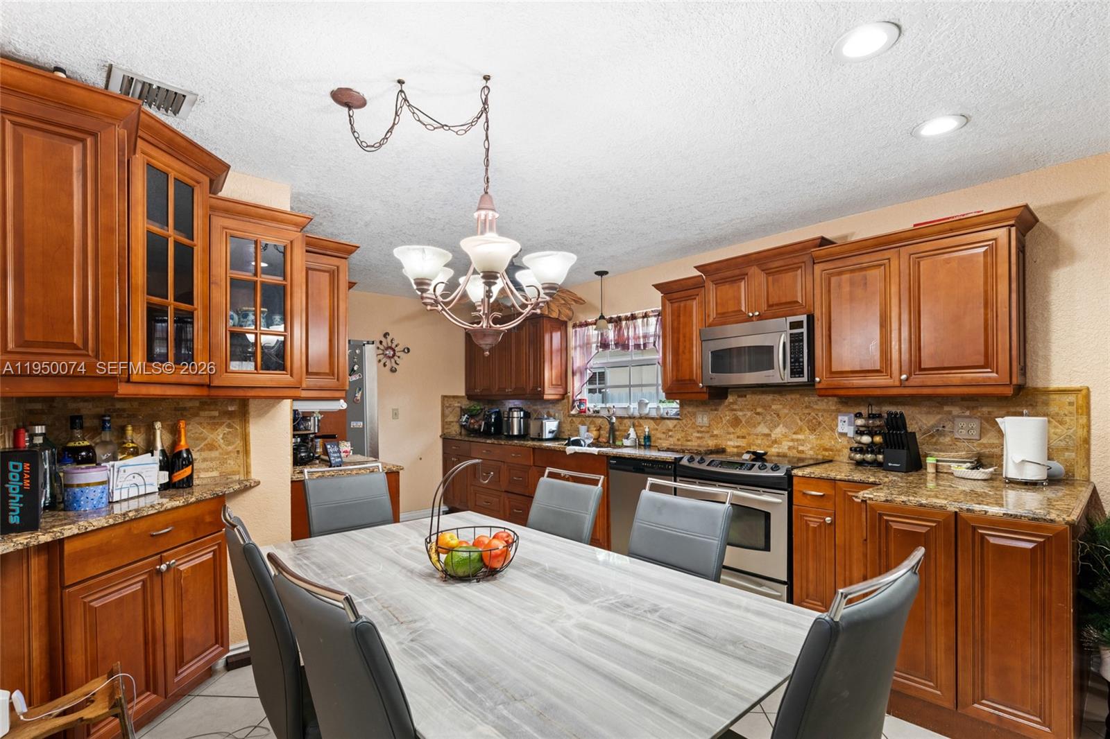 5951 Southwest 4th Street Miami, FL 33144 - Photo 11 of 23 a kitchen with stainless steel appliances granite countertop a sink dishwasher a stove a dining table and chairs with wooden floor
