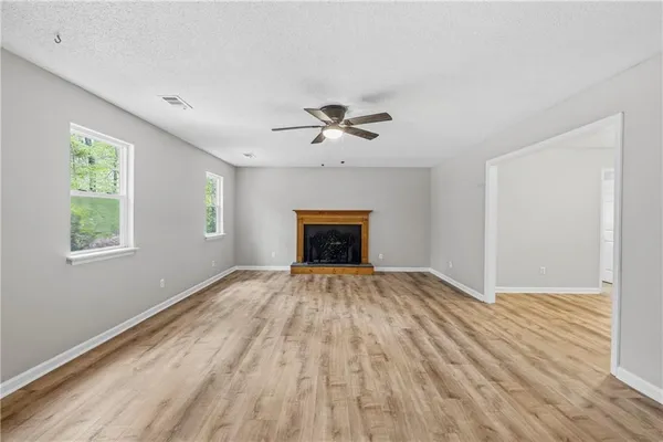 an empty room with chandelier fan and windows