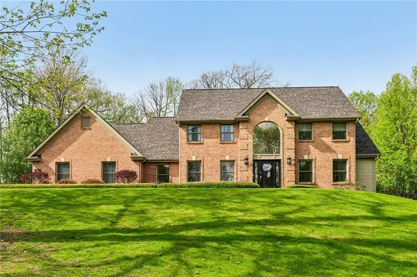 a view of a house with a big yard and large trees