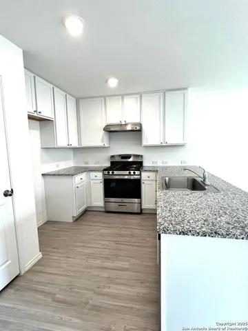 a kitchen with granite countertop a stove sink and cabinets