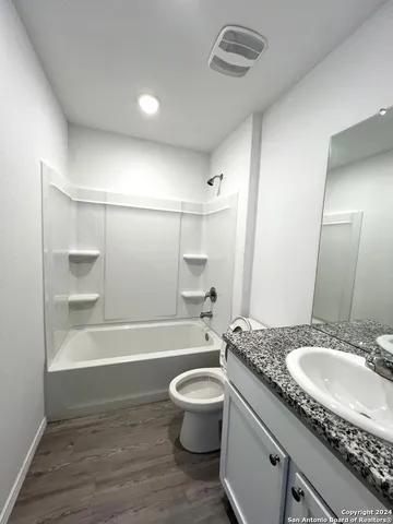 a bathroom with a granite countertop sink a toilet a mirror and bathtub