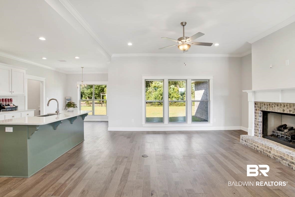 393 Garrison Boulevard Fairhope, AL 36532 - Photo 13 of 40 Unfurnished living room with ceiling fan, a fireplace, sink, and ornamental molding