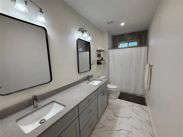 a spacious bathroom with a double vanity sink toilet mirror and shower