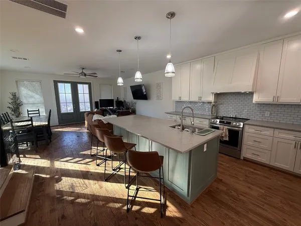 a kitchen with a stove a refrigerator a sink dishwasher with a dining table and chairs with wooden floor