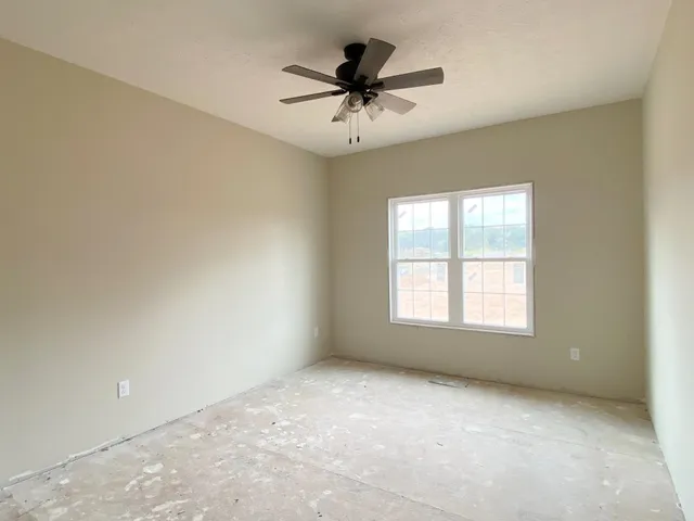 an empty room with a ceiling fan and window